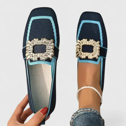Navy blue loafers with light blue trim and crystal square buckle — hand holding shoe next to foot wearing pair