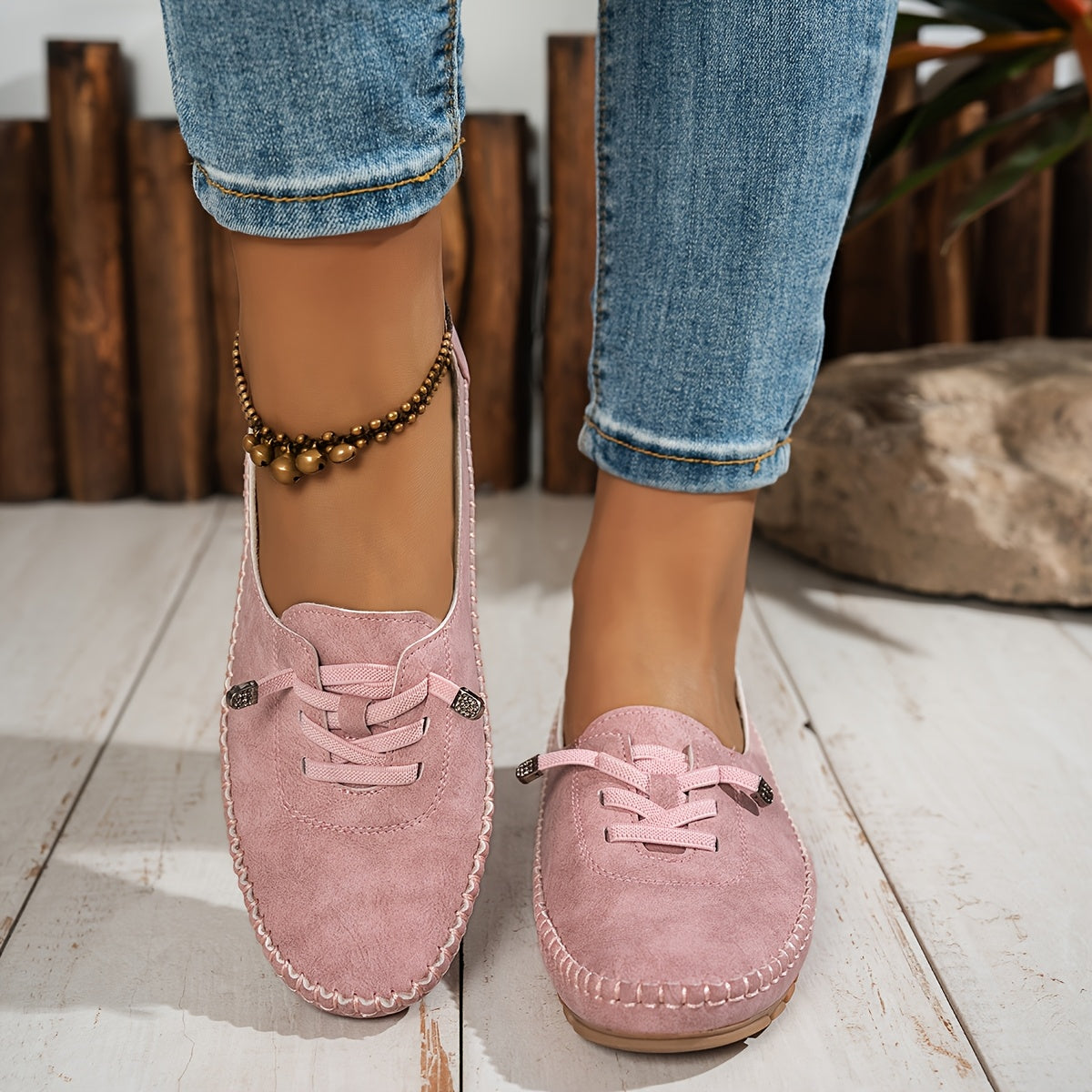 Pink suede lace-up loafers with decorative stitching on model wearing cuffed jeans — front angled view