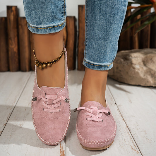 Pink suede lace-up loafers with decorative stitching on model wearing cuffed jeans — front angled view