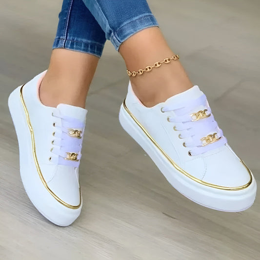 White sneakers with gold trim and chain details worn with blue jeans — front angled view